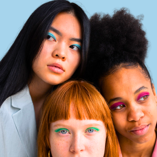 Three women with colorful eye makeup against a light blue background